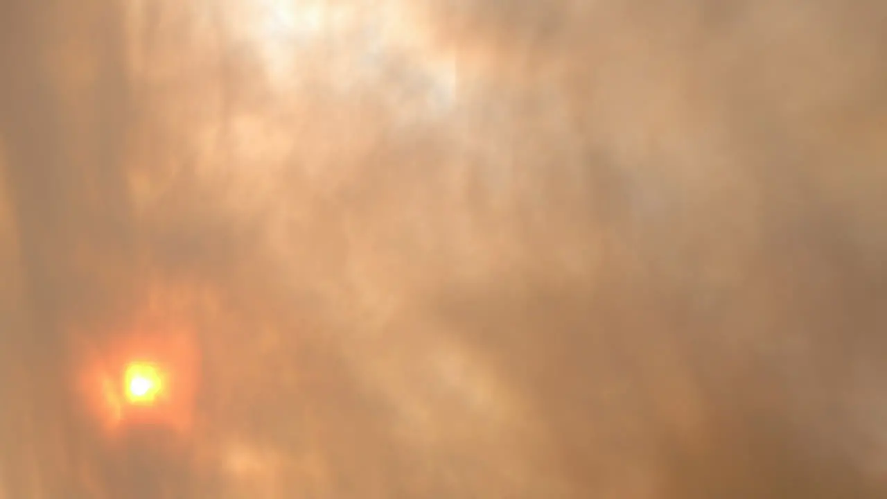 Time lapse of smoke clouds blowing in front of the sun