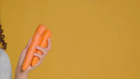 Close Up Shot of Young Adult Woman Holding Carrots