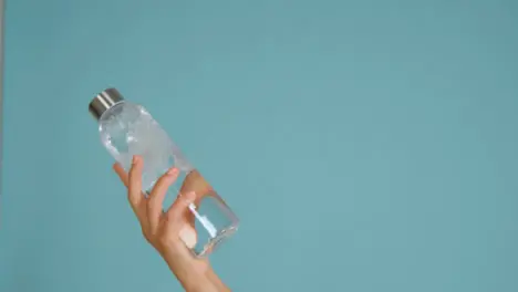 Close Up Shot of Young Womans Hand Bringing Water Bottle into Frame with Copy Space 02