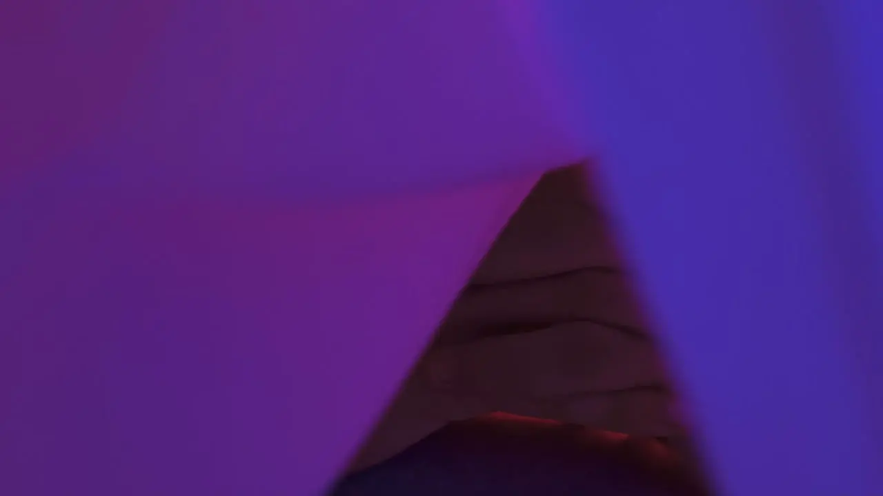 Close-up slow-motion shot of a man with clasped hands inside a tent with bright lights