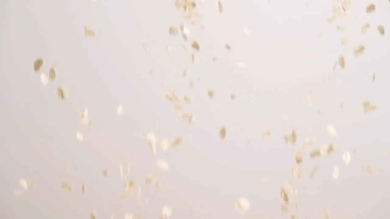 Oatmeal falling in slow motion oats raining with white backdrop in 4k