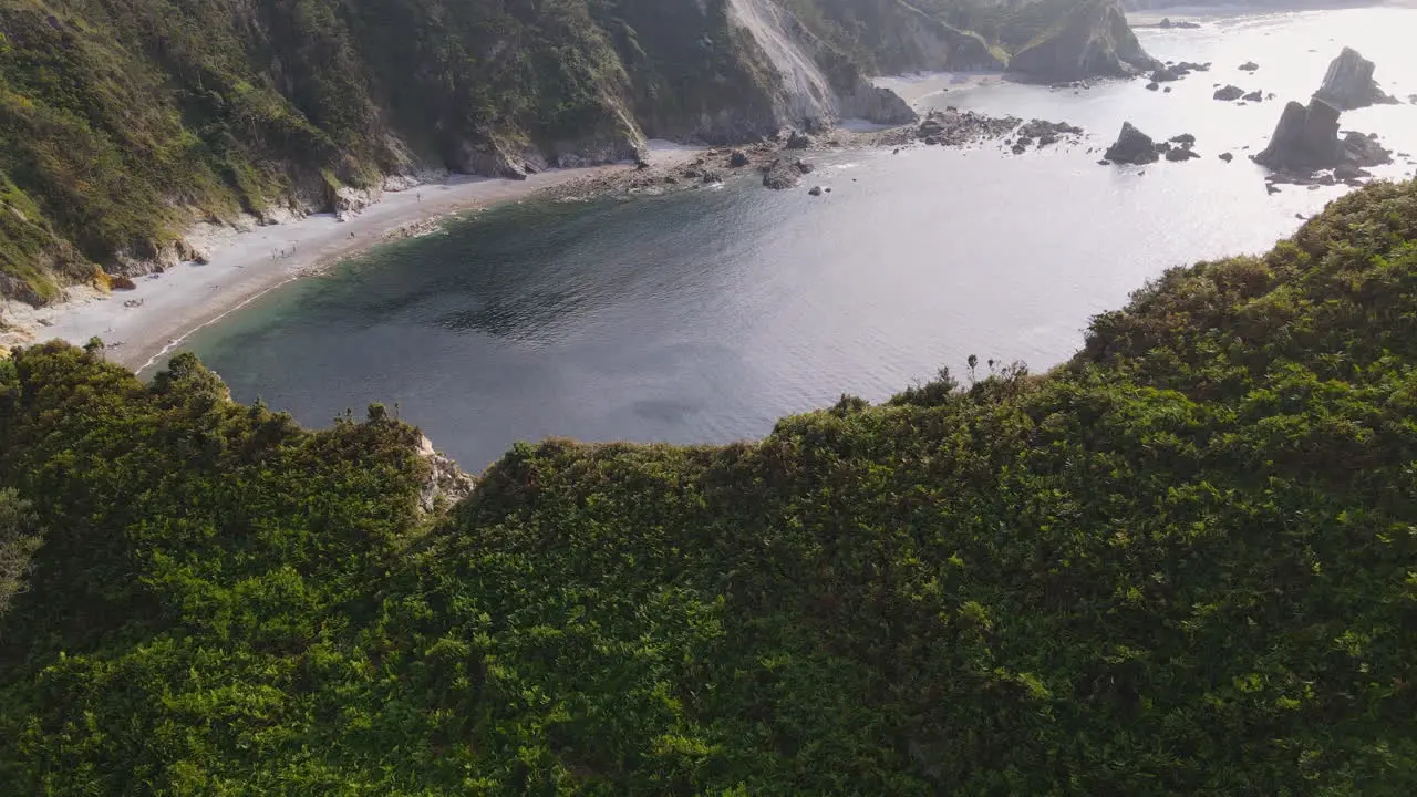 Aerial View Of Beautiful Wild Cliff Coastline On A Sunny Day While People Are On The Beach