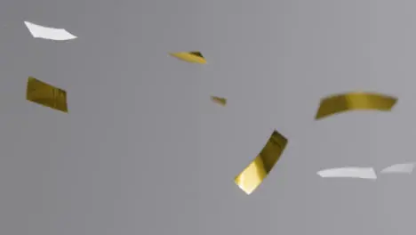 Stationary Shot of Gold and White Confetti Falling Against a Grey Background