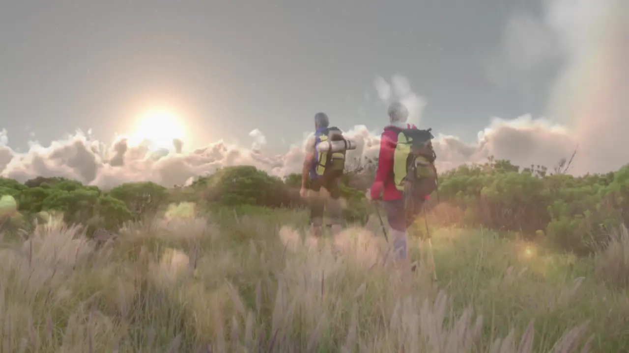 Caucasian senior couple hiking in countryside over fast moving clouds and sunset