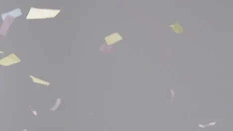 Stationary Shot of Coloured Strip Confetti Falling Against a Grey Background