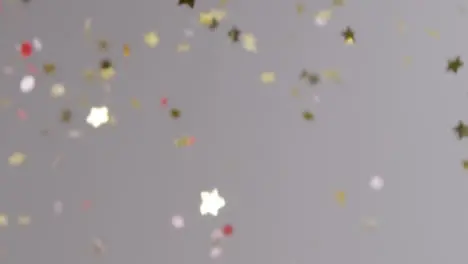 Stationary Shot of Gold and Pink Confetti Falling Against Grey Background