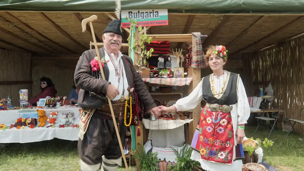 Bulgarian man and woman dress in traditional costume and pose for camera