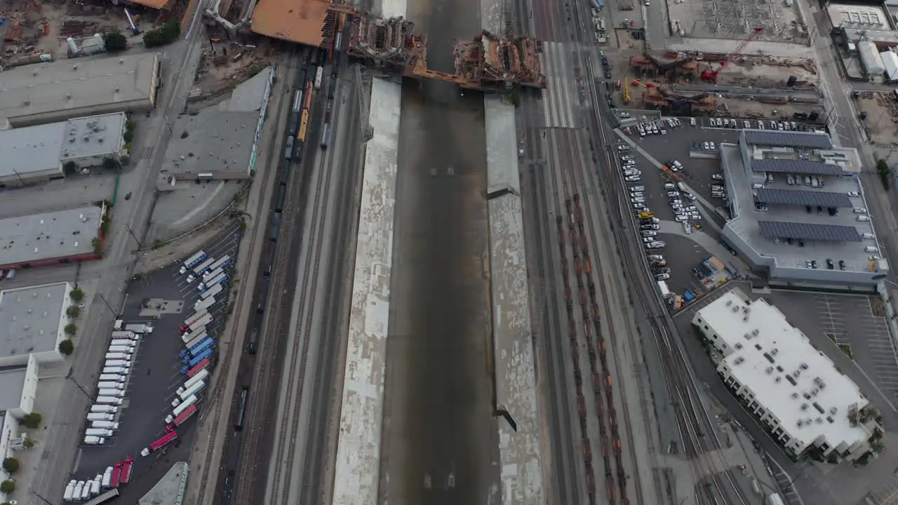 AERIAL Overhead  Birds Eye View on Los Angeles River with Water on Cloudy Overcast Sky next to Train Tracks