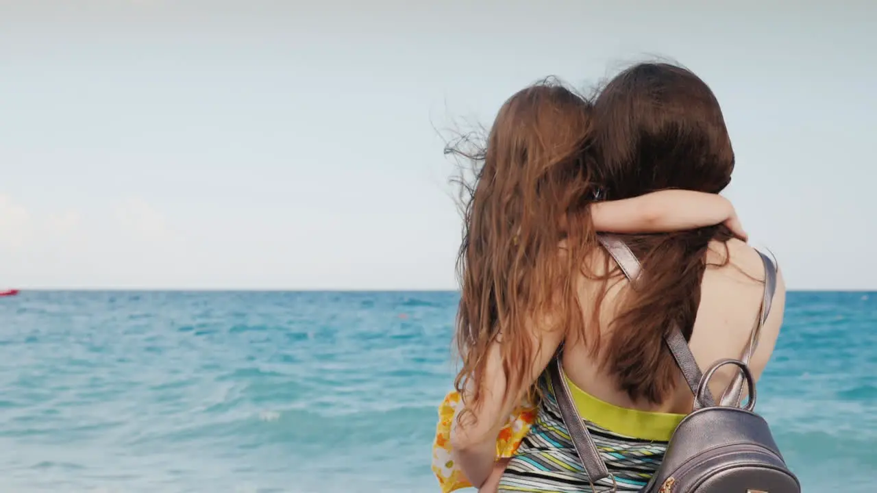 A Family Of Two People Is Sitting On The Beach And Enjoying The View Of The Sea Landscape Back View