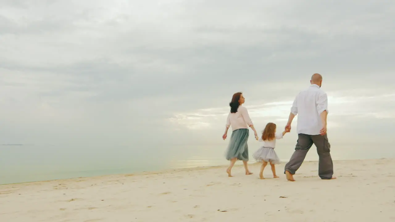 Happy Family Together Walking Along Shore Of Calm Sea