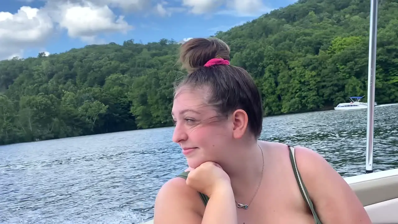 Young woman happy smiling and laughing enjoying boat ride with wind blowing in her face fun day