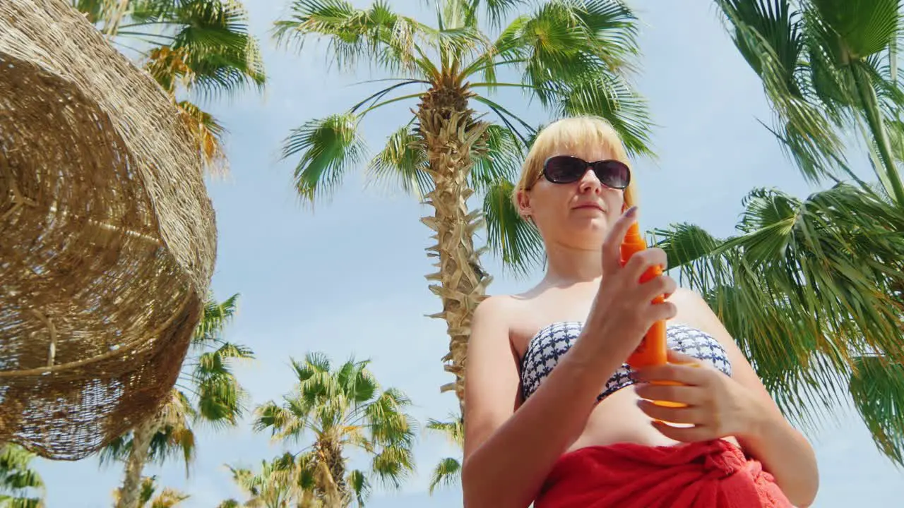 A Woman Uses The Cream From The Sun Standing On The Background Of Sky And Palm Trees