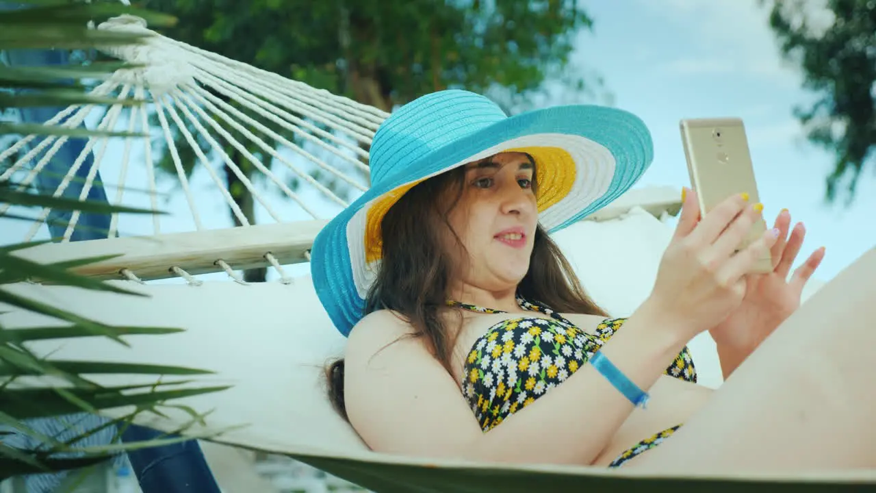 A Cute Brunette In A Wide-Brimmed Hat And In A Bikini Enjoys Relaxing In The Seaside Resort Reading 