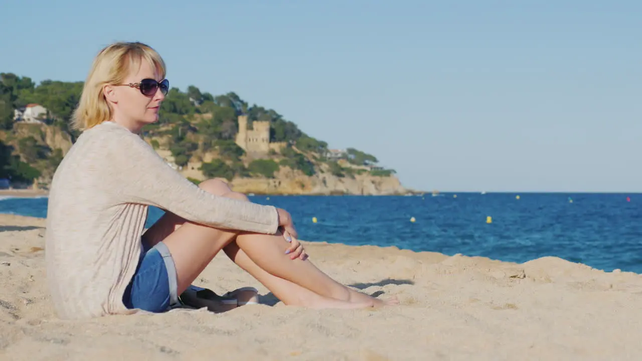 A young tourist sits on the beach by the sea looking into the distance