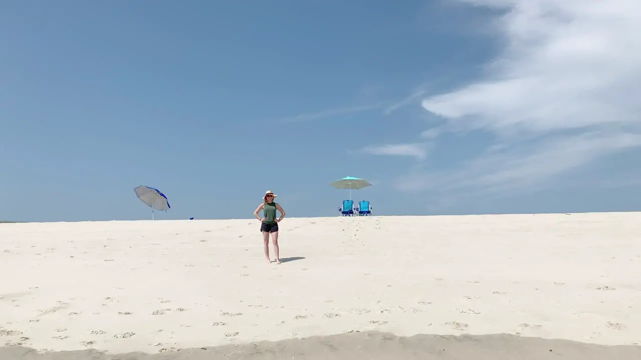 a beautiful woman is alone on the beach with two chairs and umbrellas