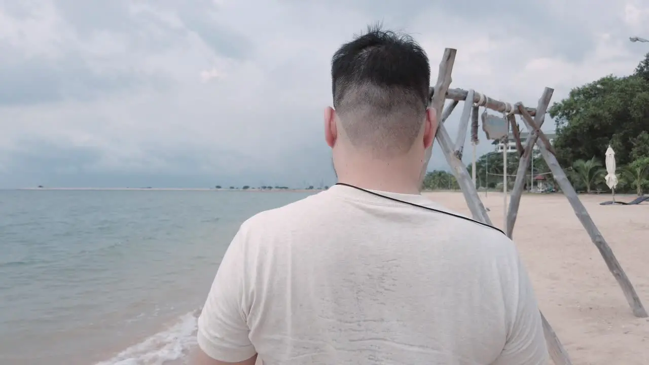 Asian man while walking on the white sand beach in summer vacation holiday time