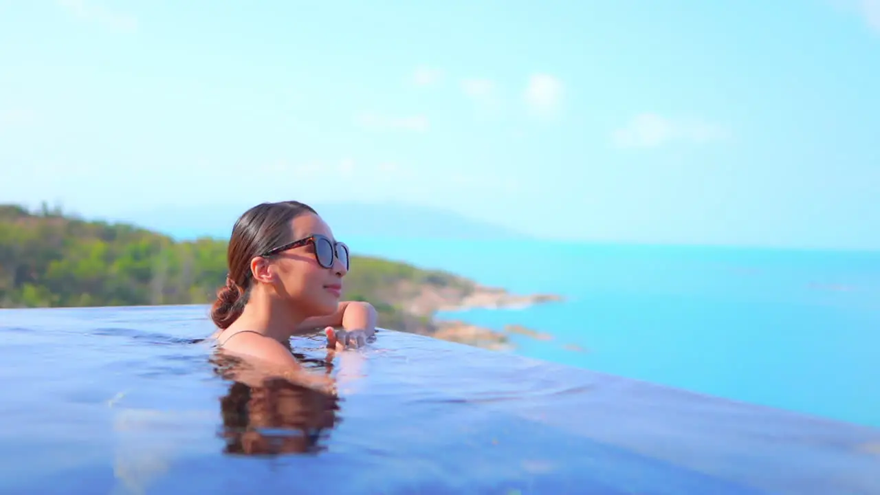 Rule of thirds A young woman chest-high in a swimming pool moves toward the edge of the pool to look out at the ocean view