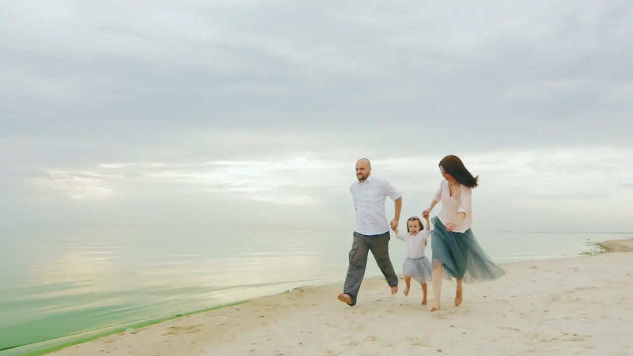 Family Fun Mom Dad And Daughter Run On The Beach