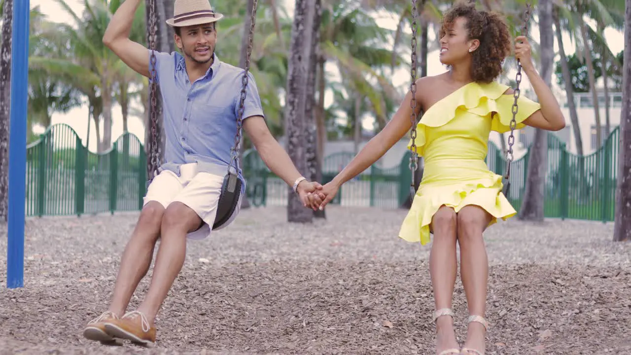 Couple holding hands on swing