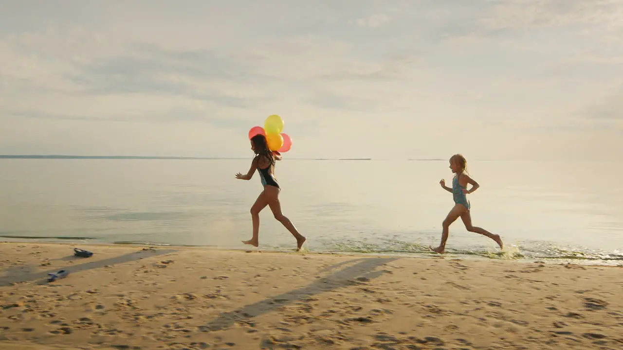 Happy Childhood Two Sisters Running Around Each Other On The Beach Have Fun Steadicam Slow Motion 