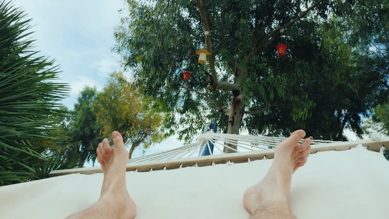 A Man Is Resting In A Hammock A First-Person View In The Frame Only The Legs Are Visible 4k Video