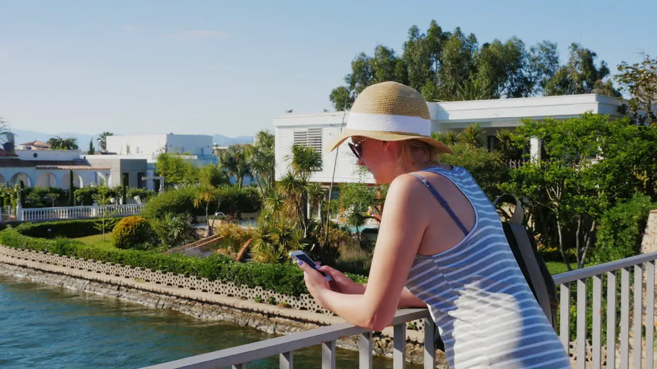 Tourist With The Phone Standing On The Bridge Over The Canal In Empuriabrava Spain Steadicam Shot