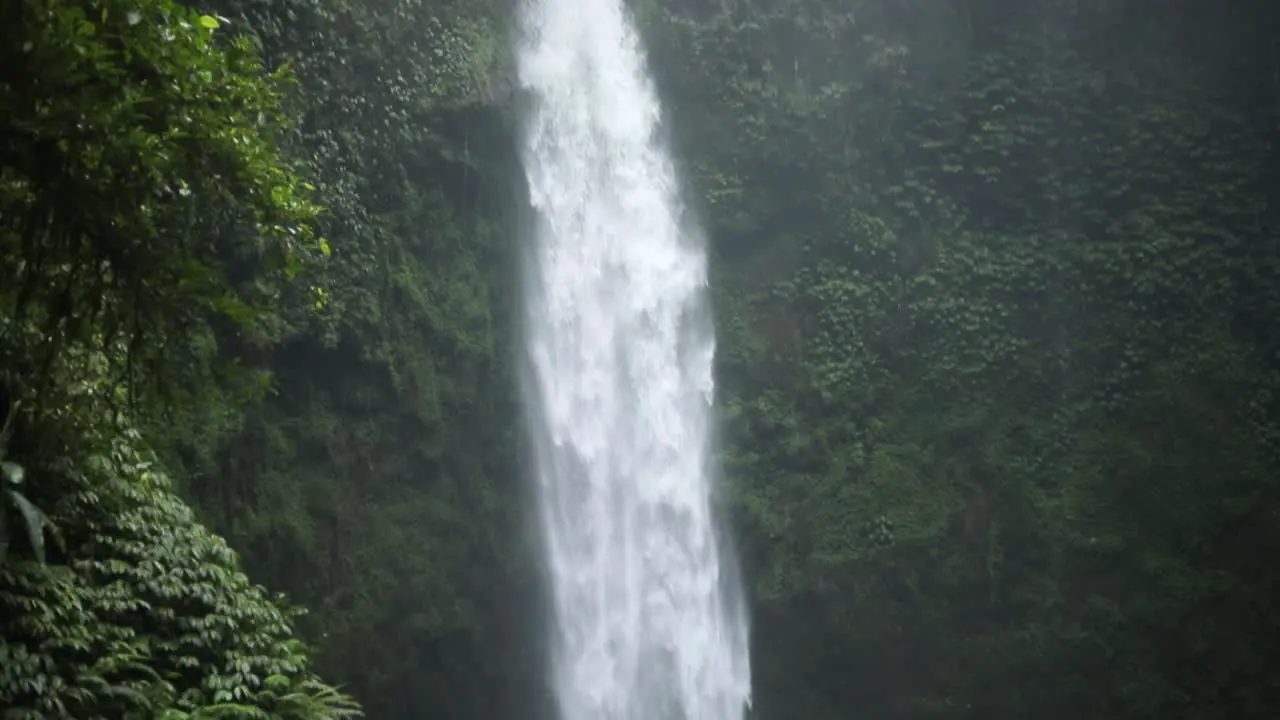 Slow motion panning up shot in front of a gushing NungNung Waterfall in Bali Indonesia following a rain storm