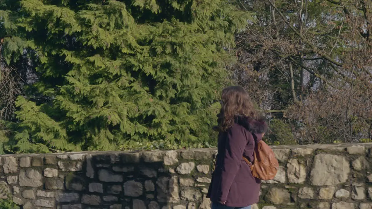 Young woman walks next to a large green forest on her trip through Europe