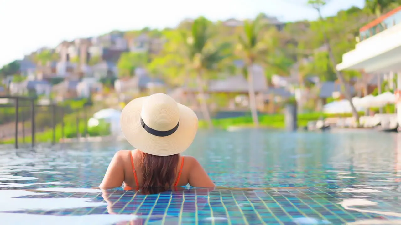 Back of Beautiful Woman Inside Swimming Pool Water at a Tropical Resort in Miami slow-motion handheld