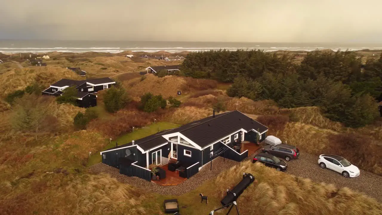 Modern black and white summer house in the countryside by the ocean aerial orbit