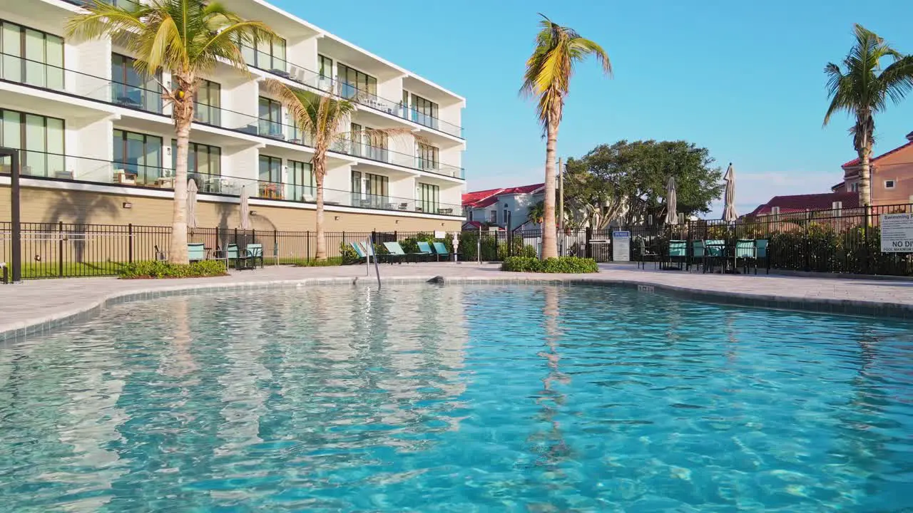 A close up drone shot of the pool water with loungers and tables with umbrellas near by in Melbourne Florida