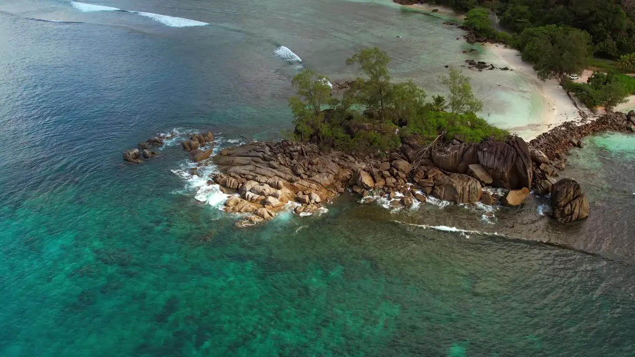 Drone moving towards rock boulders near the beach of Port glaud Mahe Seychelles Slow motion