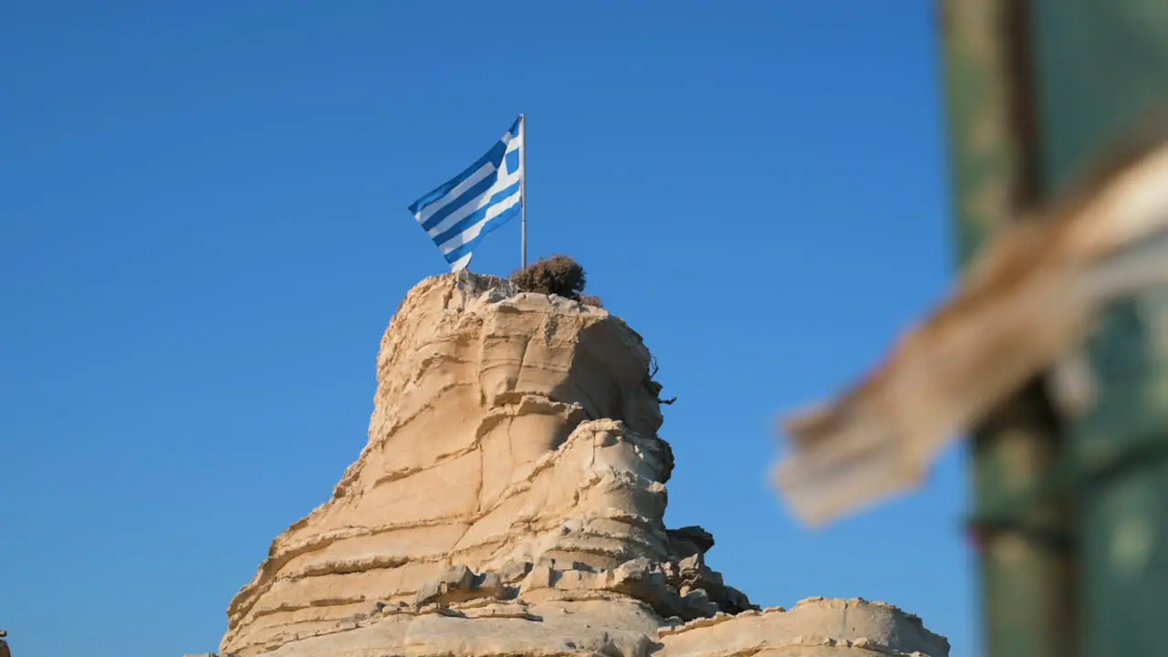 Reveal of the national flag of Greece mounted on the top of a rock plateau