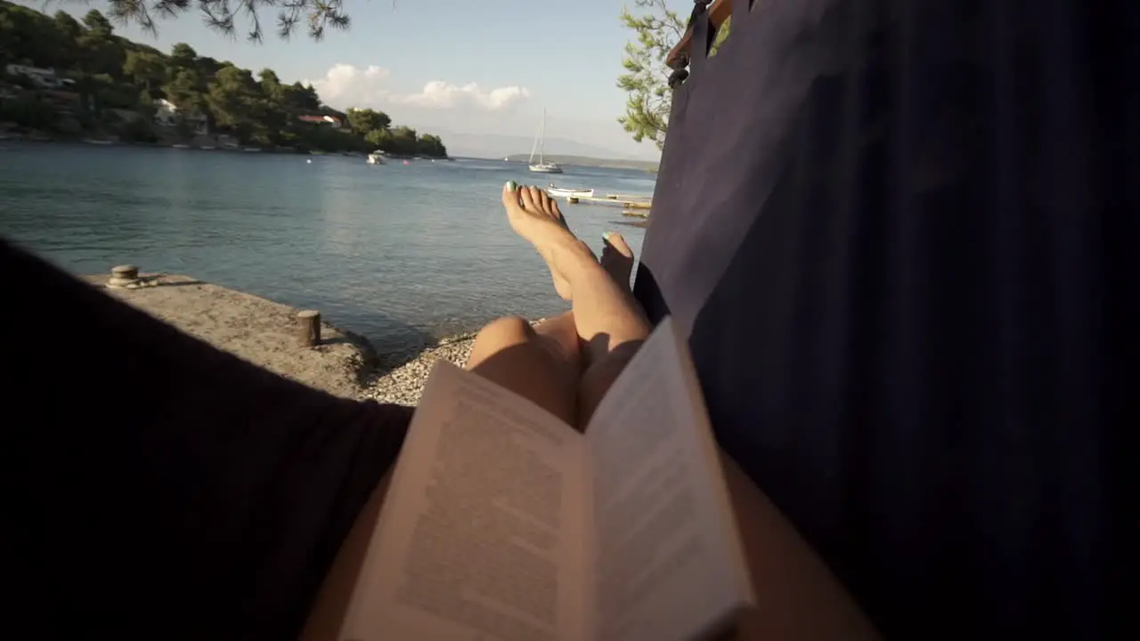 Woman reading book in hammock at the beach