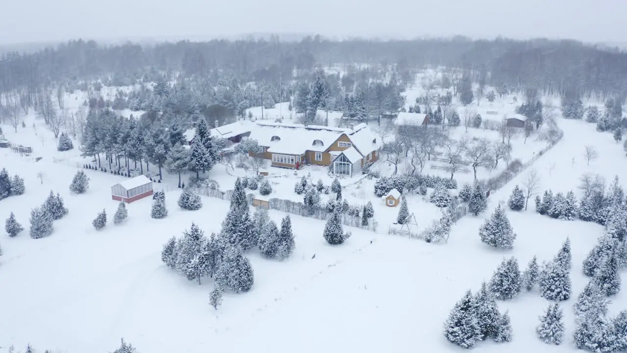 Winter wonderland aerial of a country house in a snow blizzard during Christmas