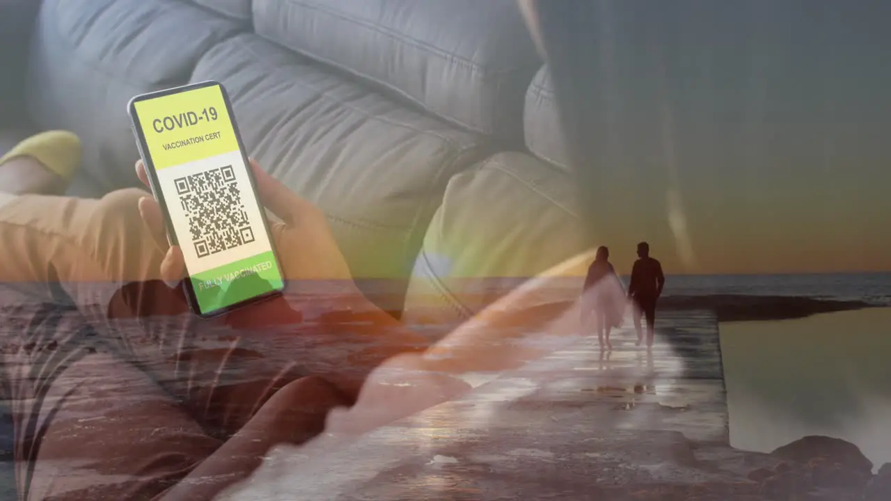 Animation of woman with covid passport on smartphone over couple on beach