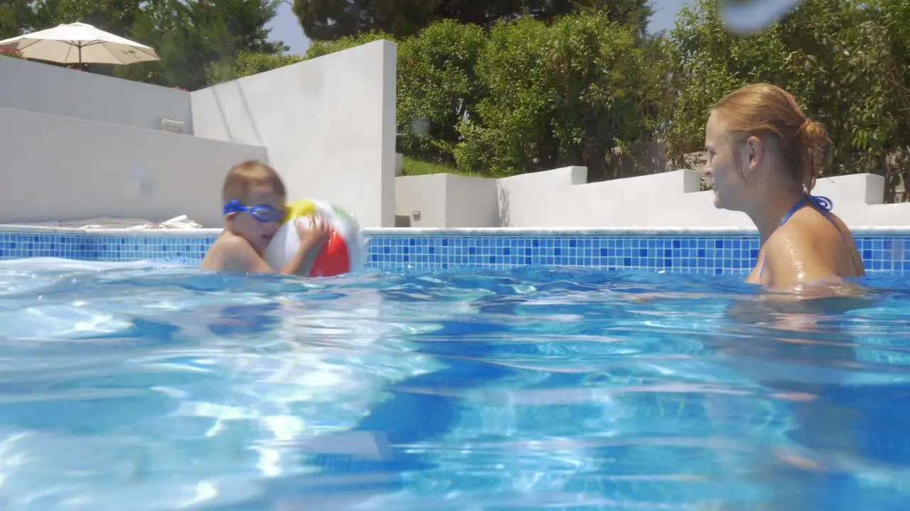 Mother and son playing with ball in the pool