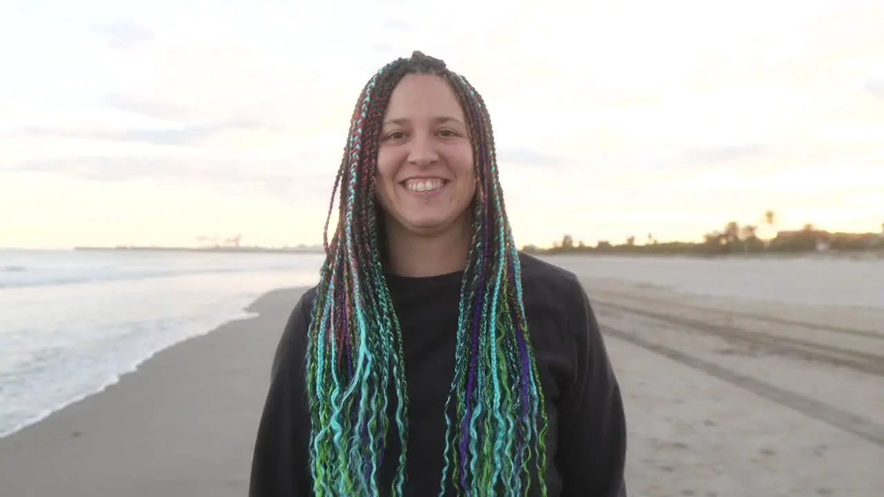 woman with braids laughs looking at camera at sunset on the beach