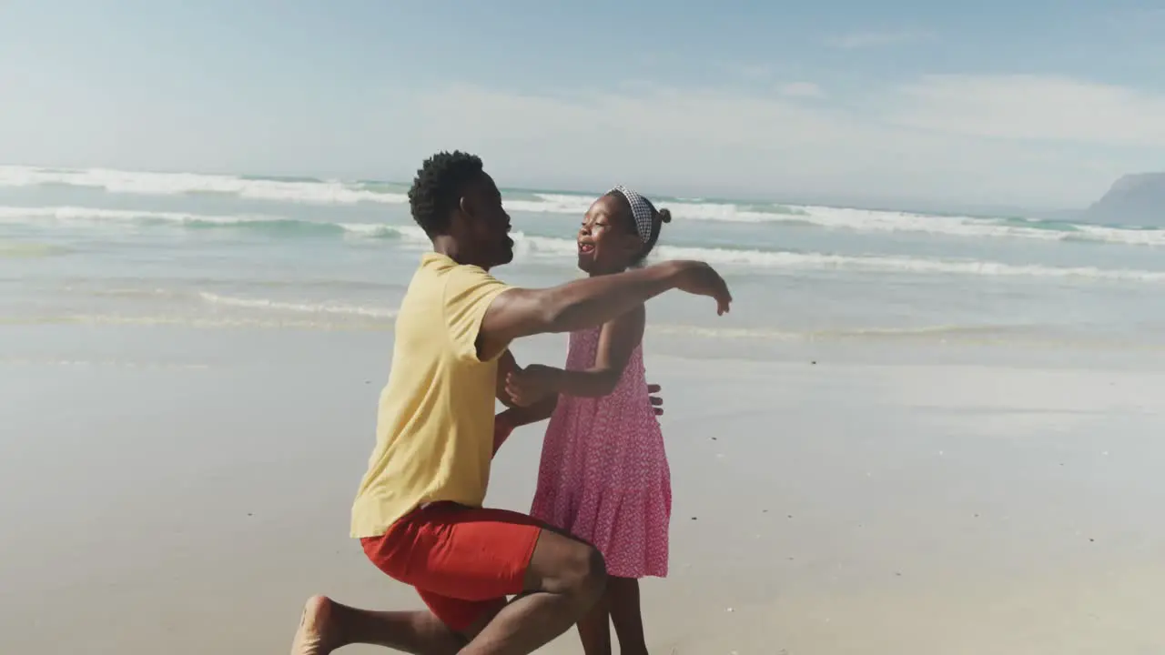 African american father and daughter hugging each other at the beach