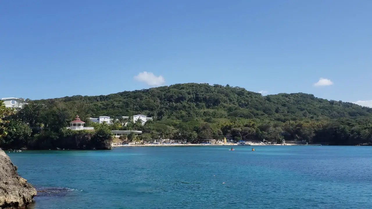 two people in kayaks in ocean bay by tropical island