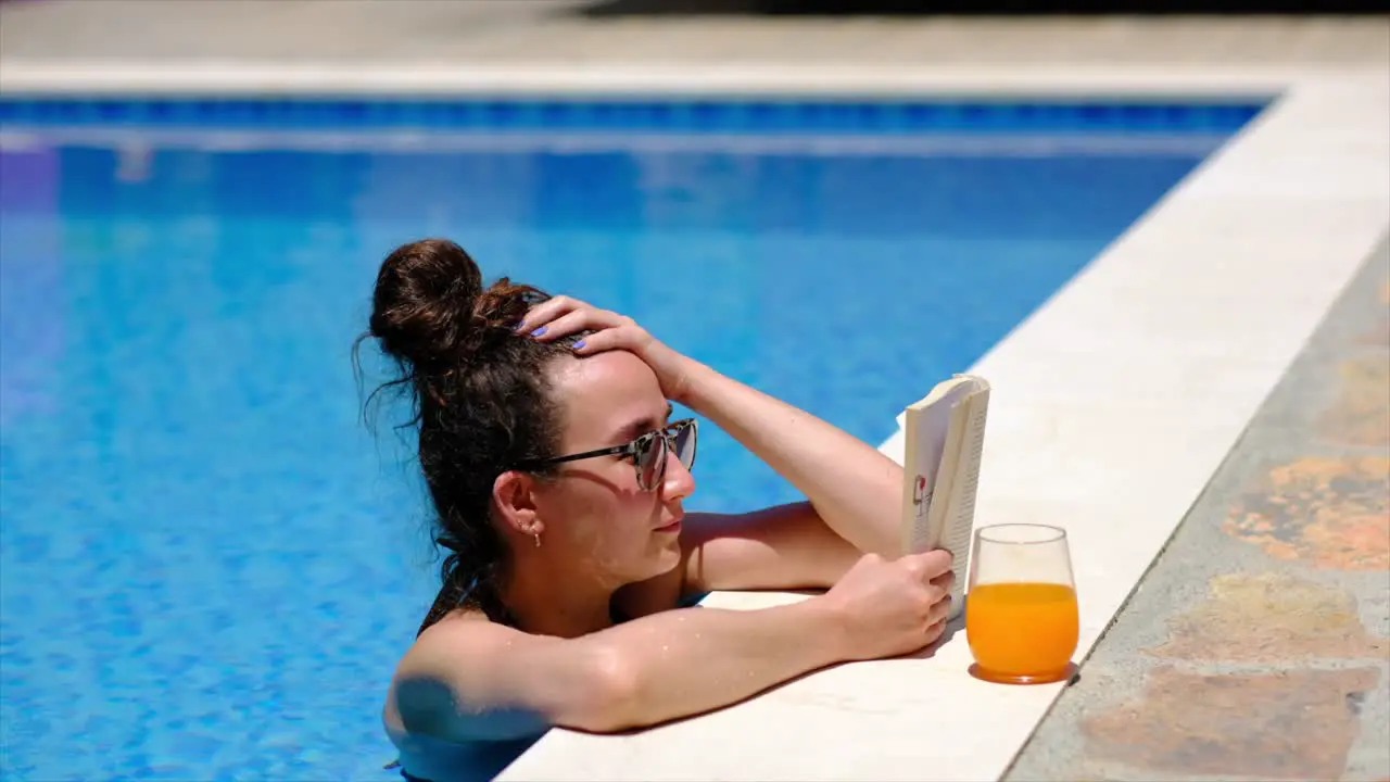 woman is reading a book by the pool