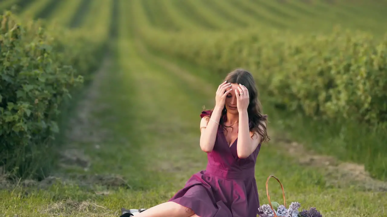 beautiful girl in a crimson dress sitting in a field