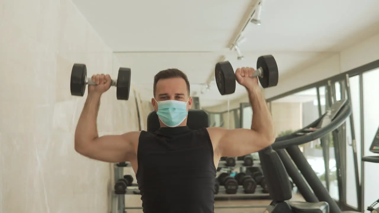 Young Strong Man With Face Mask Lifts Weights And Exercises In The Gym