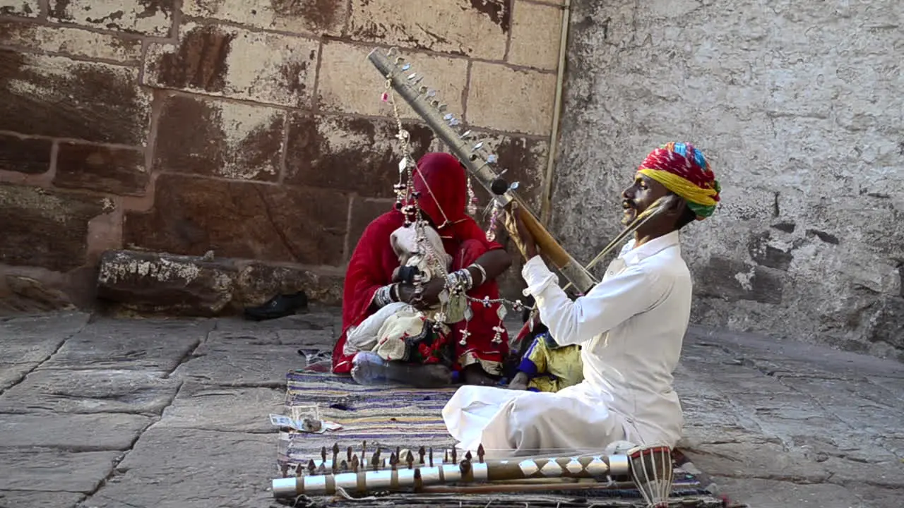 Traditional Folk singer signing song performing playing violin in public with his family daylight outdoor side view