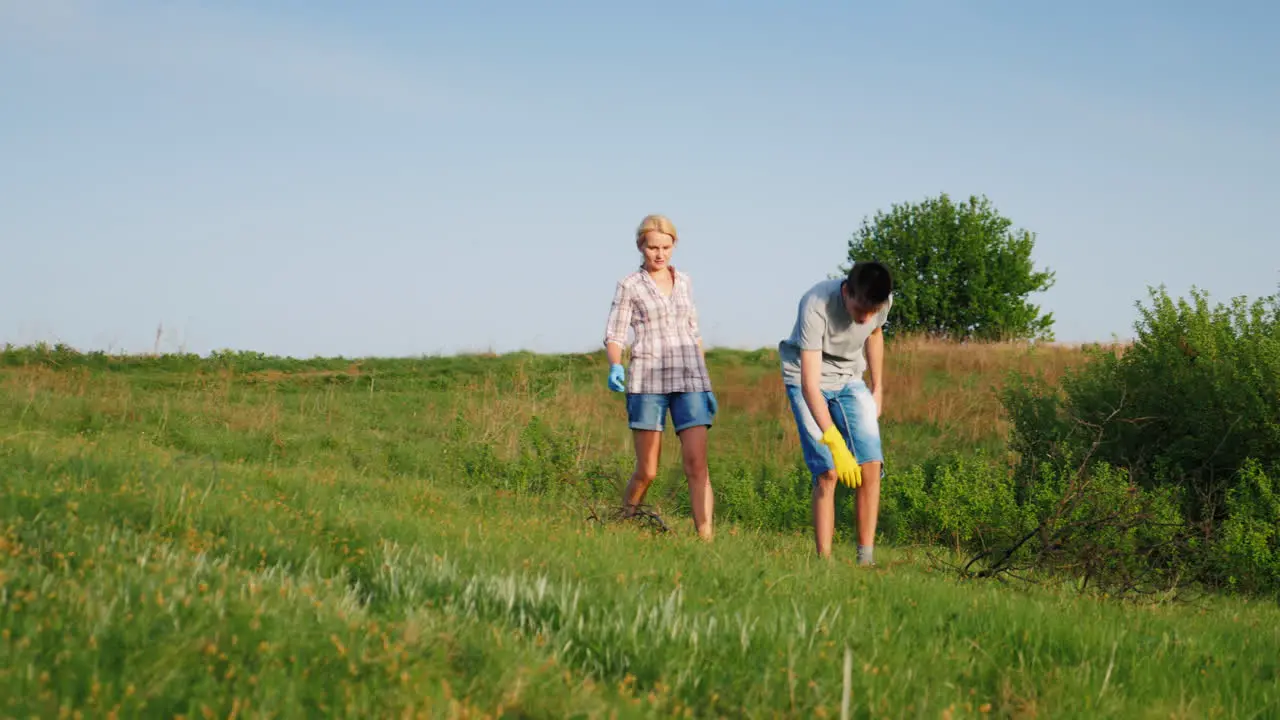 A Woman With Her Teenage Son Is Cleaning Up The Garbage In The Meadow