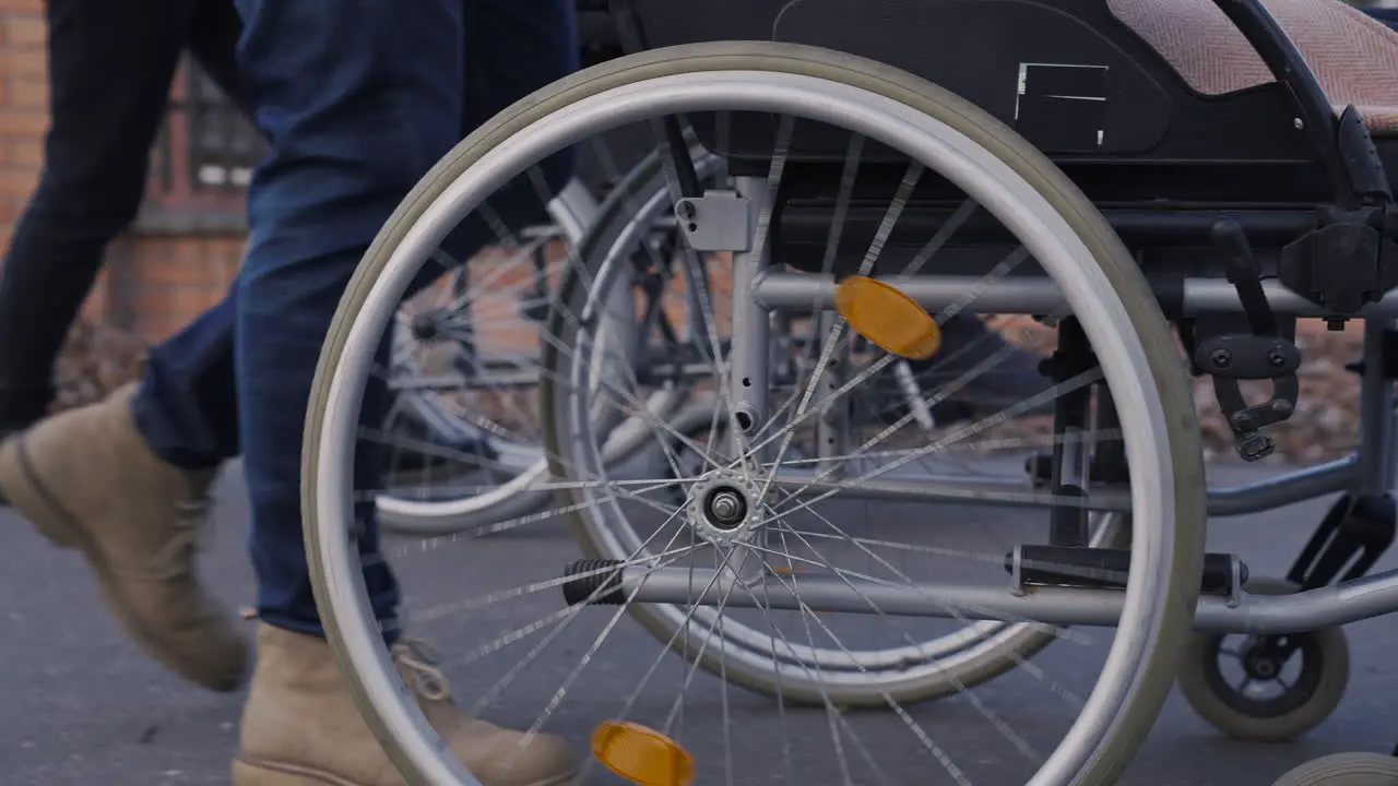 Camera Focuses On Wheel Of A Wheelchair Spinning On A Walk In The Street