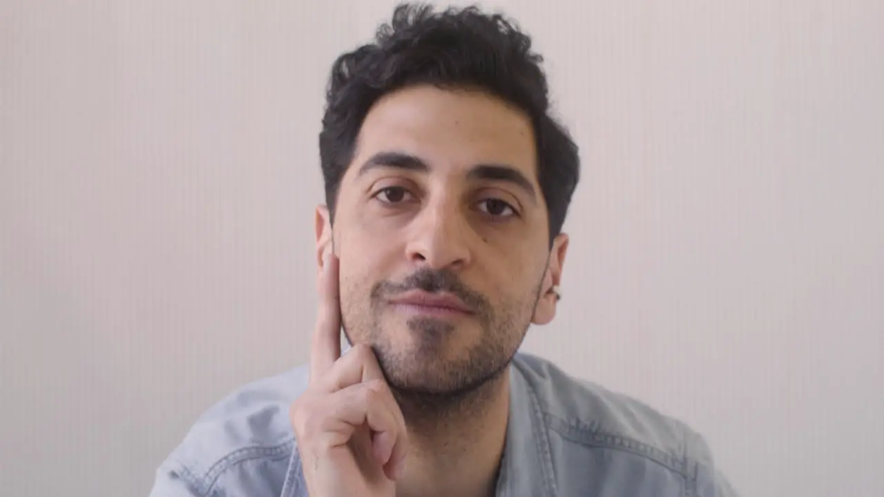 Attractive Dark Haired Man Sitting And Looking At The Camera In A Room