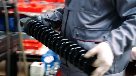 Worker inserting large spring shock absorber into machine for processing