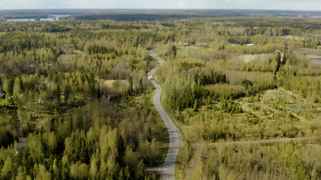 Aerial tilt down drone shot of a car and a bus on a road in the Porvoo archipelago on a sunny spring day in the Saaristo of Uusimaa Finland