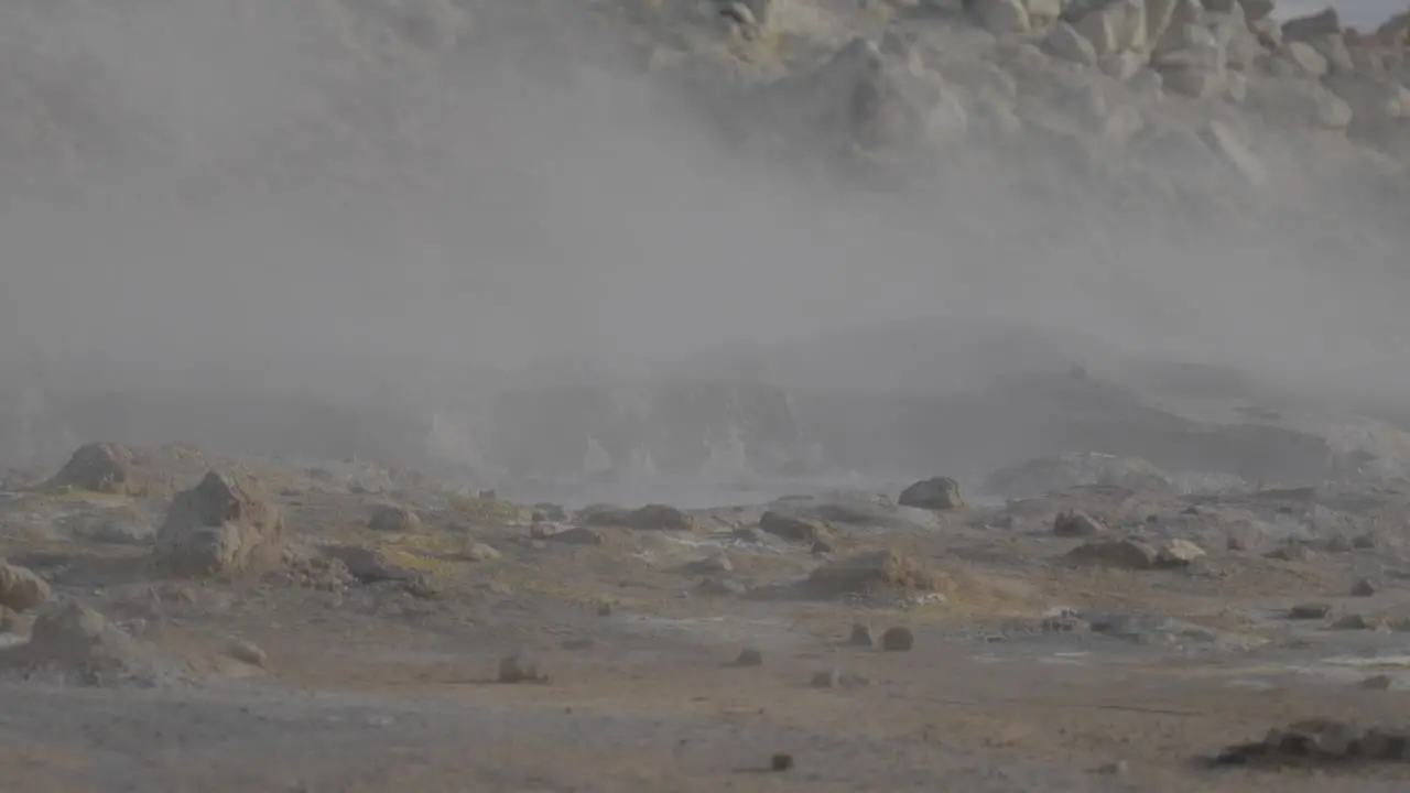 Low shot of a natural spring boiling releasing clouds of steam in Iceland